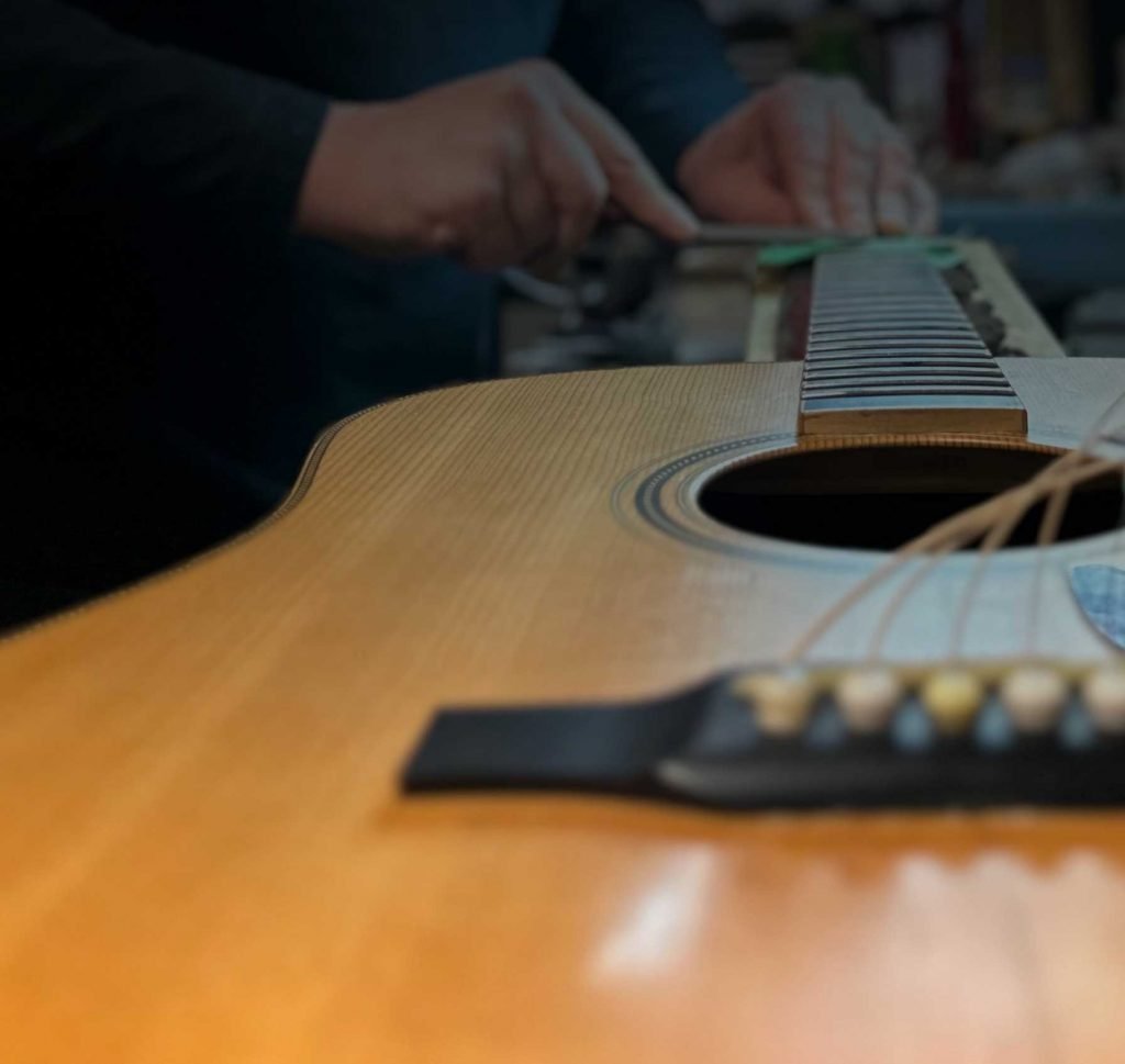 Guitar technician, Nathan Mcmurdo, performing fretwork services on an acoustic guitar
