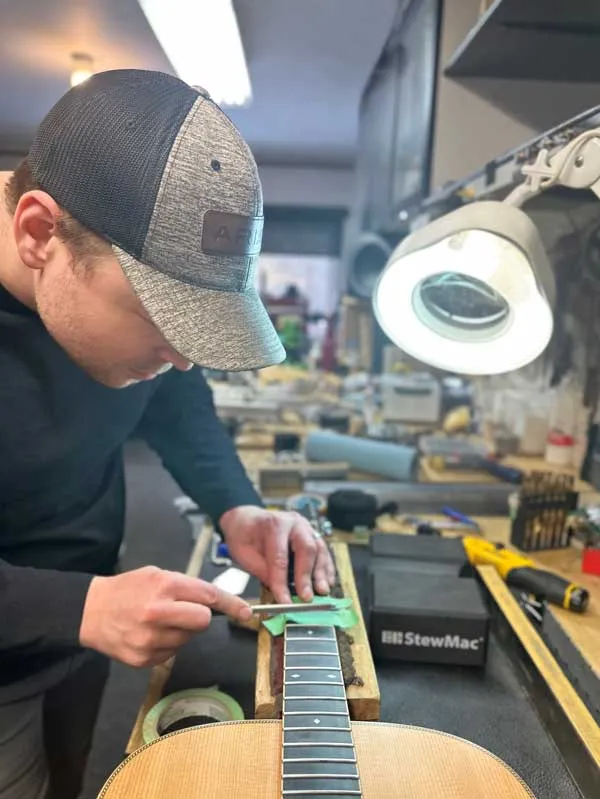 Guitar technician, Nathan Mcmurdo, performing fretwork services on an acoustic guitar